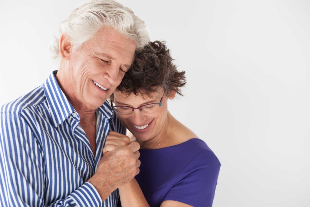 Affectionate senior couple embracing and dancing. Happy man with closed eyes holding hand of wife. They loving each other. Relationship or tender feeling concept